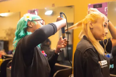 A Pro Way student practices ironing a clients hair.